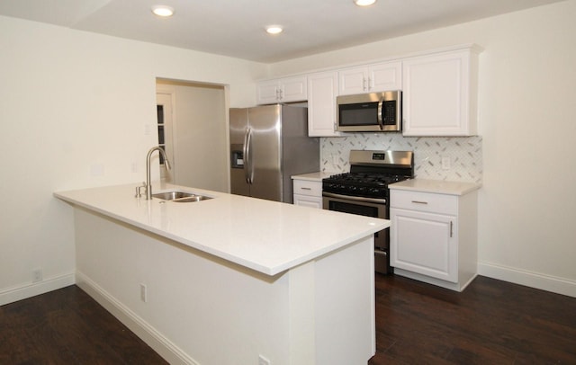kitchen with a sink, decorative backsplash, a peninsula, appliances with stainless steel finishes, and dark wood-style flooring