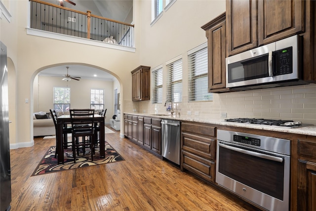 7305 Caladium Dr, Mckinney, TX 75070 - kitchen with appliances with stainless steel finishes, a ceiling fan, arched walkways, and a towering ceiling