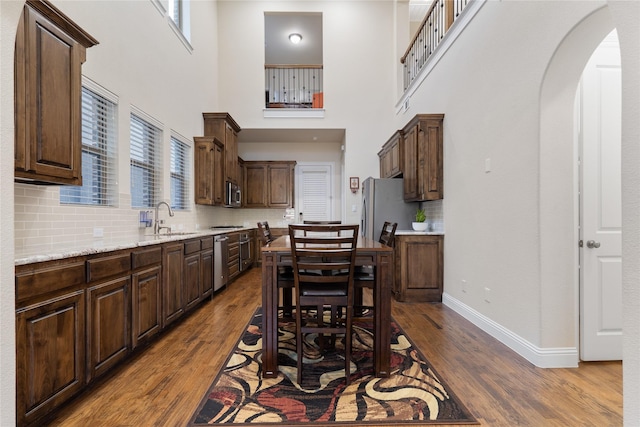 7305 Caladium Dr, Mckinney, TX 75070 - dining room with dark wood-style floors, a towering ceiling, arched walkways, and baseboards
