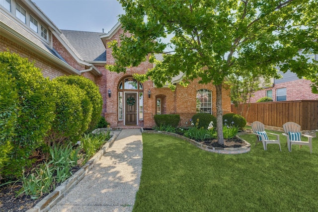 1809 Cotton Mill Dr, Mckinney, TX 75072 - property entrance with fence, brick siding, a yard, and roof with shingles