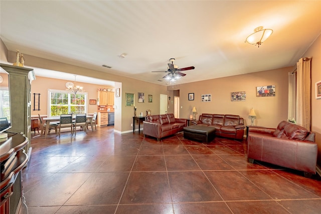 living area featuring ceiling fan with notable chandelier, dark tile patterned flooring, and visible vents