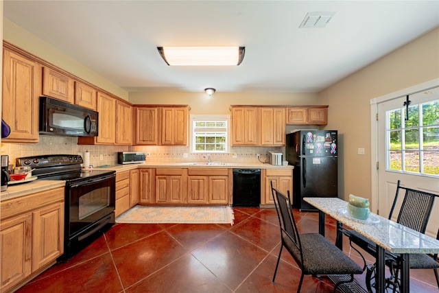 kitchen featuring a wealth of natural light, a sink, visible vents, dark tile patterned flooring, and black appliances