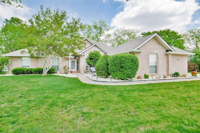 ranch-style home with brick siding, roof with shingles, and a front yard