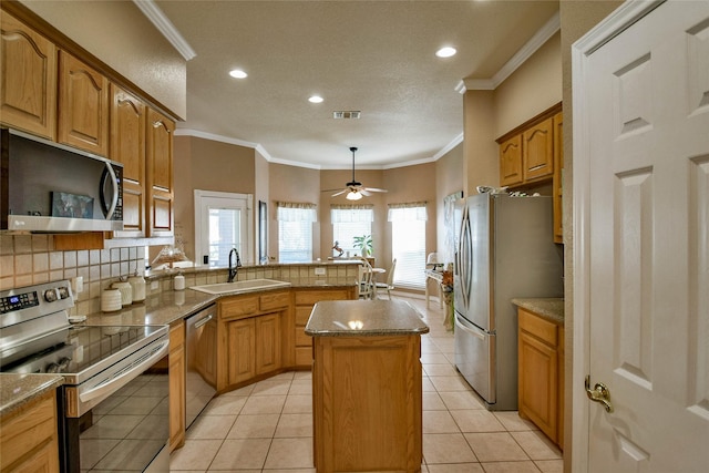 kitchen featuring a peninsula, a sink, visible vents, crown molding, and appliances with stainless steel finishes