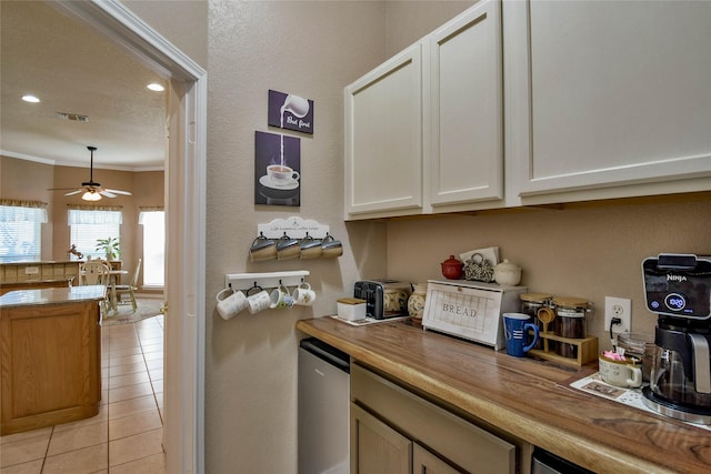 kitchen featuring wood counters, light tile patterned flooring, visible vents, and ornamental molding