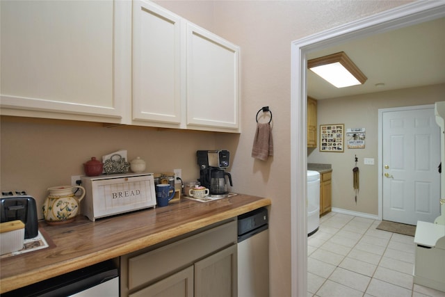 kitchen featuring stainless steel dishwasher, baseboards, washer / clothes dryer, wood counters, and light tile patterned floors