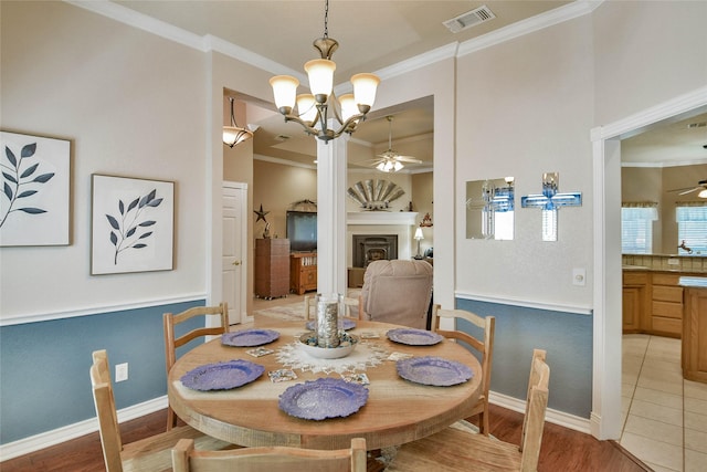 dining space featuring light wood finished floors, baseboards, visible vents, ceiling fan with notable chandelier, and ornamental molding