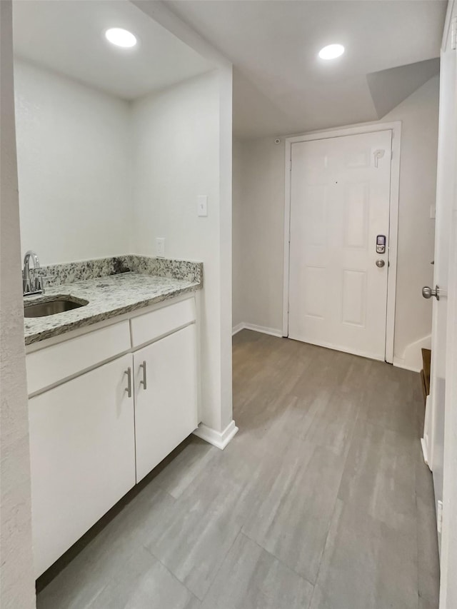 interior space featuring baseboards, a sink, and recessed lighting