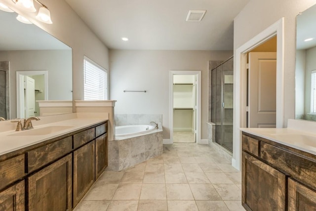 full bath with two vanities, a sink, visible vents, a shower stall, and a garden tub
