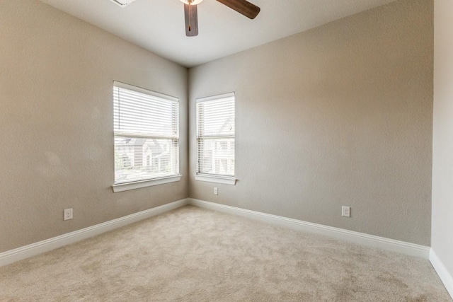 carpeted spare room with ceiling fan and baseboards