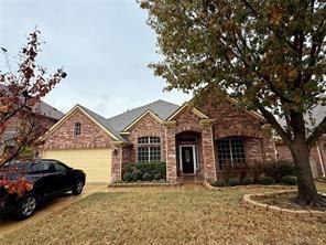 ranch-style home featuring concrete driveway, a front lawn, brick siding, and a garage