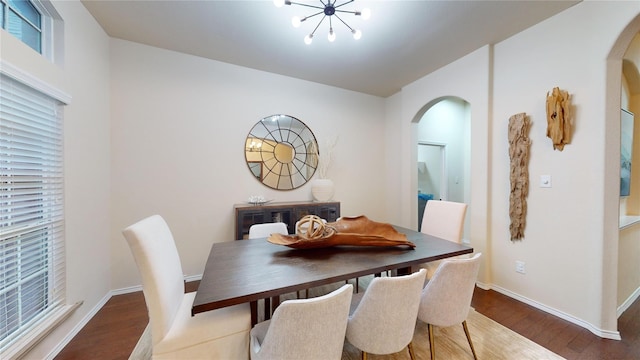 dining room with an inviting chandelier, baseboards, wood finished floors, and arched walkways