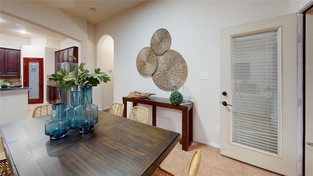 dining space with arched walkways and light tile patterned floors