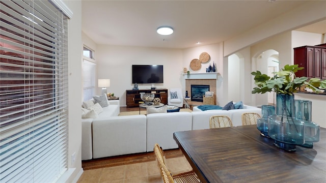 living area with arched walkways and a tile fireplace