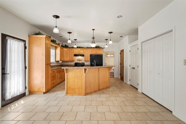kitchen with a breakfast bar area, range, a kitchen island, under cabinet range hood, and black fridge with ice dispenser