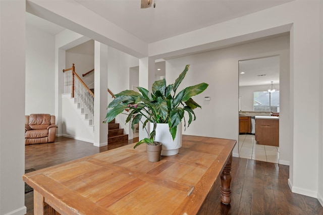 dining area with baseboards, hardwood / wood-style floors, and stairs