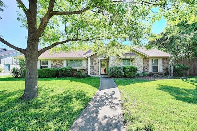 single story home featuring fence, a front yard, and stone siding