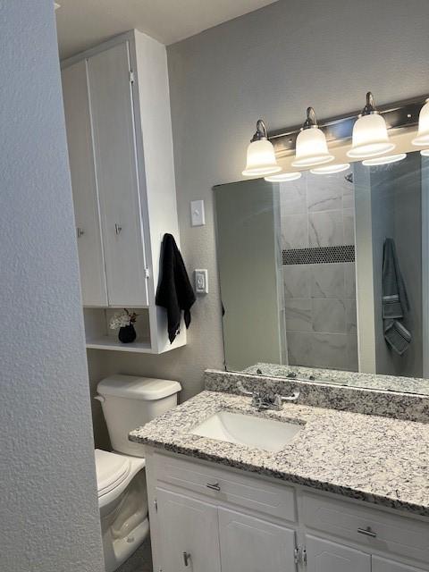 bathroom featuring a textured wall, vanity, and toilet