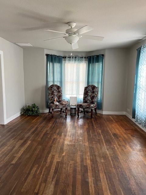 living area featuring baseboards, a ceiling fan, and wood finished floors