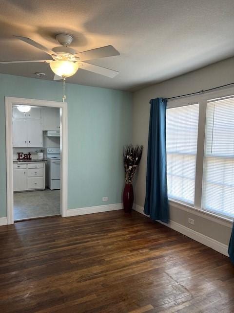spare room with baseboards, a ceiling fan, and dark wood-style flooring