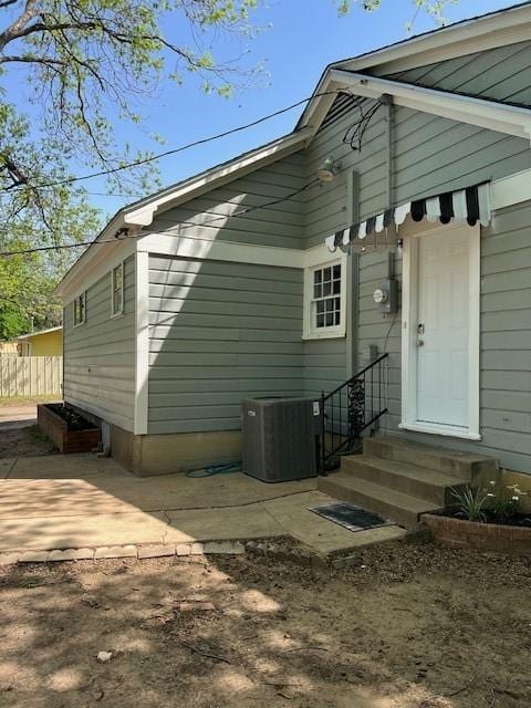 view of side of home featuring fence, a patio, entry steps, and central AC unit