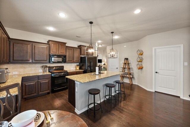 14116 Rabbit Brush Ln, Fort Worth, TX 76052 - kitchen featuring dark wood-style floors, decorative backsplash, black appliances, a chandelier, and a kitchen bar