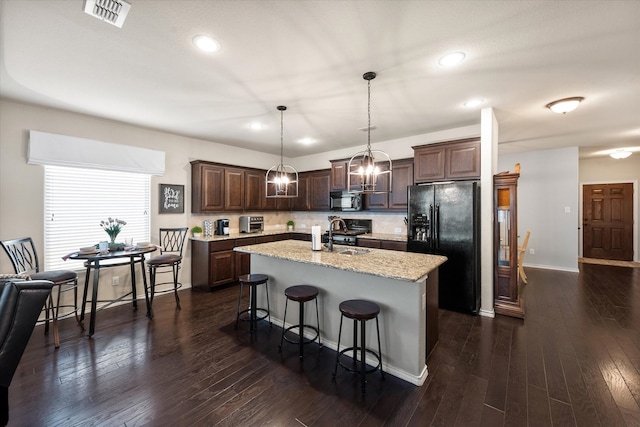 14116 Rabbit Brush Ln, Fort Worth, TX 76052 - kitchen featuring an island with sink, dark brown cabinets, visible vents, stainless steel microwave, and black fridge with ice dispenser