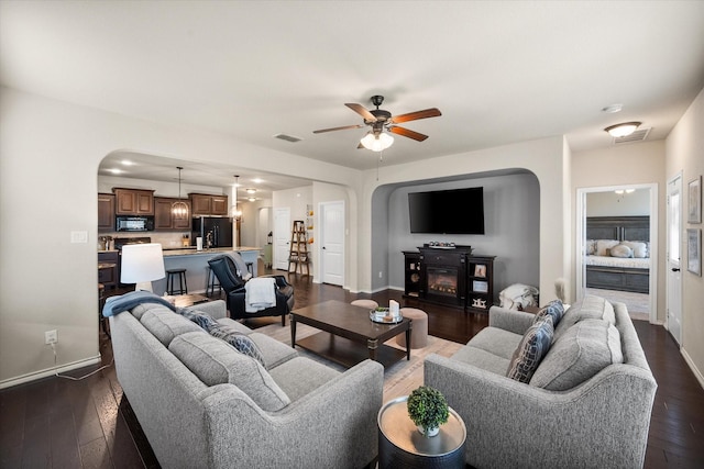 14116 Rabbit Brush Ln, Fort Worth, TX 76052 - living room with a ceiling fan, arched walkways, baseboards, dark wood-type flooring, and visible vents
