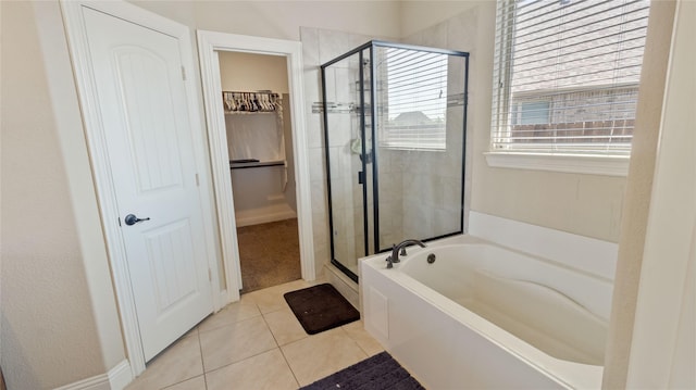 full bathroom featuring a garden tub, tile patterned flooring, a walk in closet, and a stall shower