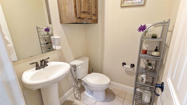bathroom with toilet, tile patterned flooring, a sink, and baseboards