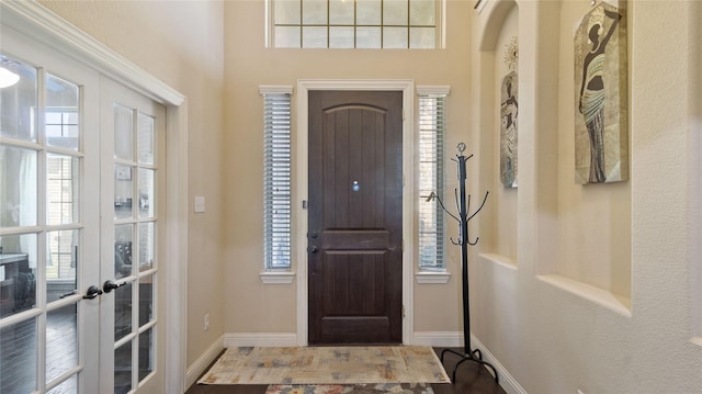 foyer entrance featuring baseboards, a healthy amount of sunlight, and french doors