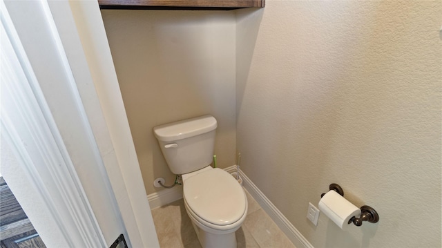 bathroom with toilet, baseboards, and tile patterned floors