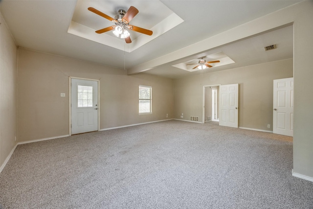spare room featuring a raised ceiling, visible vents, carpet flooring, and ceiling fan