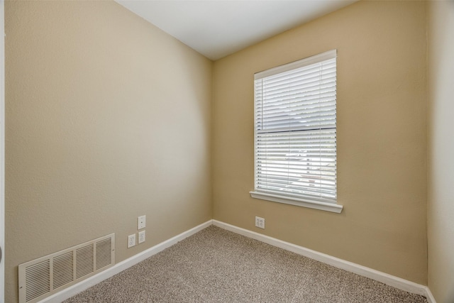 carpeted spare room featuring baseboards, visible vents, and a healthy amount of sunlight