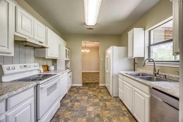 kitchen with a sink, under cabinet range hood, white appliances, white cabinetry, and stone finish floor