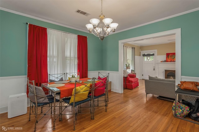 dining room with wood finished floors, visible vents, a chandelier, and a wainscoted wall