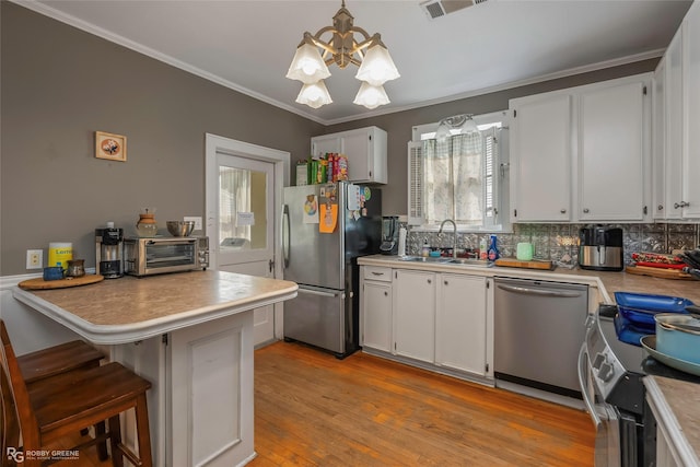 kitchen with a chandelier, white cabinets, appliances with stainless steel finishes, and a sink