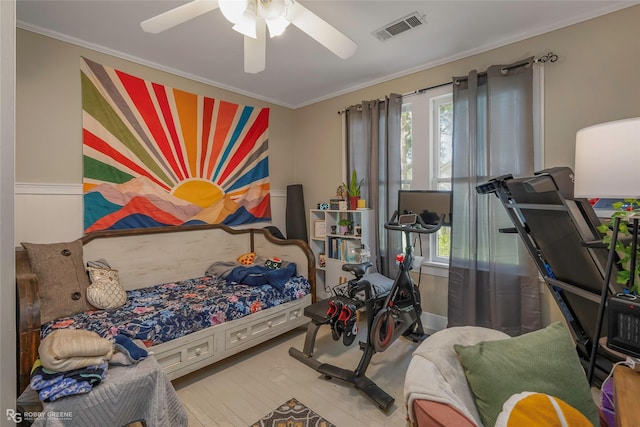 bedroom with wood finished floors, visible vents, ornamental molding, and multiple windows