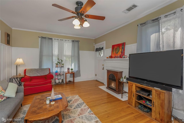 living room with wood finished floors, visible vents, a wainscoted wall, and ceiling fan