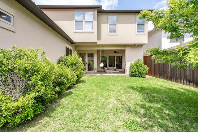 rear view of house featuring fence, a ceiling fan, a lawn, a patio, and stucco siding