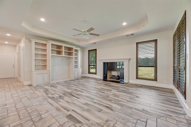 1281 Vz County Road 2120, Canton, TX 75103 - unfurnished living room with a ceiling fan, a fireplace with flush hearth, a tray ceiling, baseboards, and visible vents