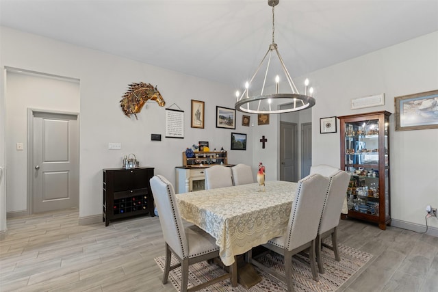 dining area featuring an inviting chandelier, light wood-style floors, and baseboards