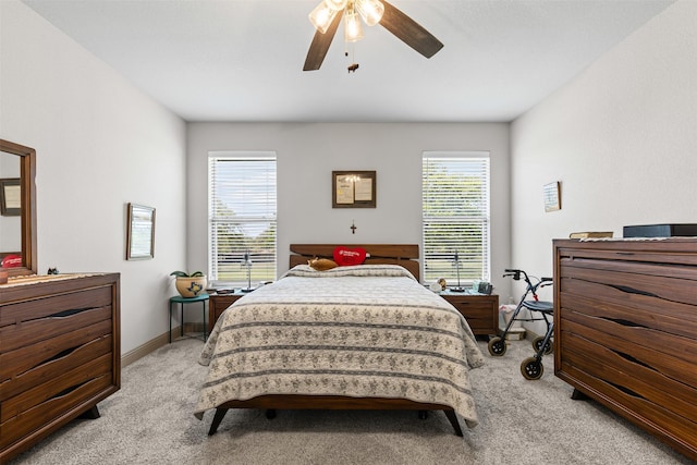 bedroom with a ceiling fan, baseboards, and light carpet