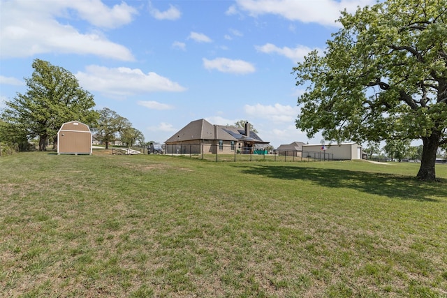 view of yard with an outdoor structure, fence, and a storage shed