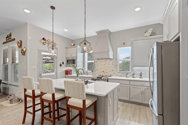 kitchen with custom exhaust hood, tasteful backsplash, a sink, stainless steel appliances, and light countertops