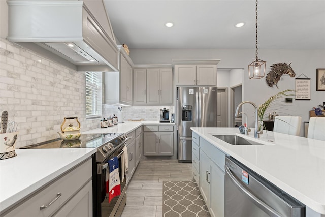 kitchen with stainless steel appliances, light countertops, a sink, decorative backsplash, and custom exhaust hood