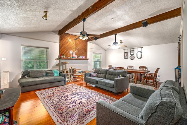 living room with vaulted ceiling with beams, wood finished floors, and a textured ceiling