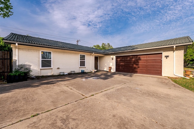 ranch-style home featuring concrete driveway, brick siding, a tiled roof, and a garage
