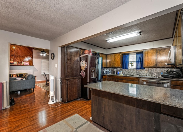 kitchen featuring a textured ceiling, a sink, black fridge, dishwasher, and dark wood-type flooring