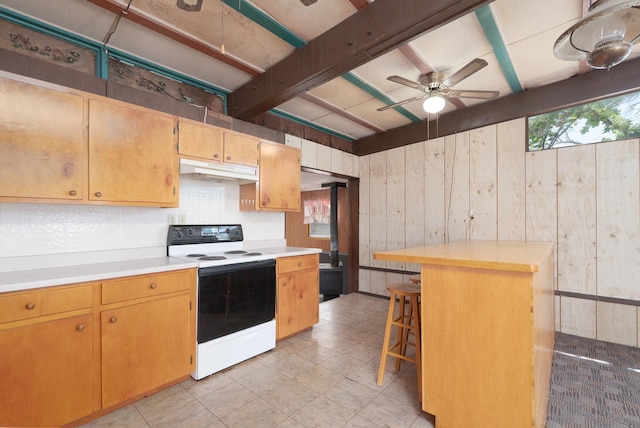 kitchen featuring a ceiling fan, electric stove, a breakfast bar, light countertops, and wood walls